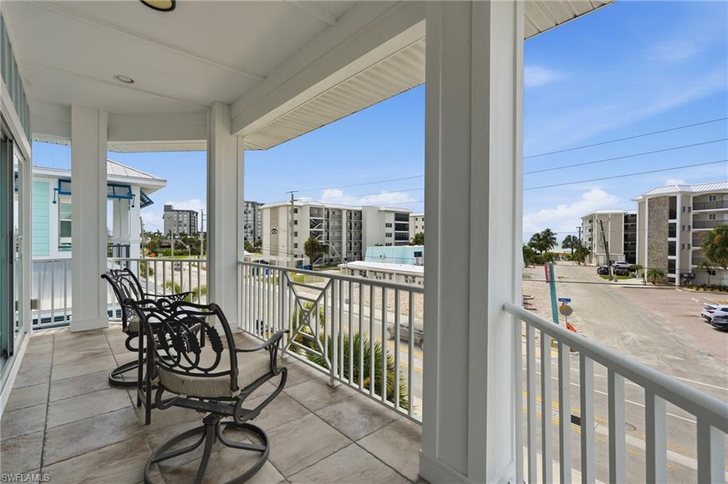 Covered balcony featuring tile flooring and white railing - Virtually Edited Image
