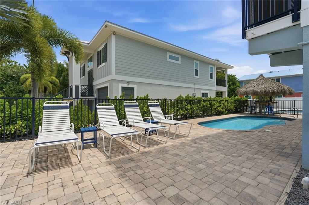 Paver patio with a built-in swimming pool, surrounded by a black metal fence and mature landscaping - Virtually Edited Image