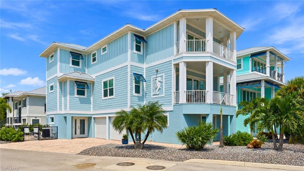 Multi-story residence featuring light blue siding, white trim, a paver driveway, an integrated two-car garage, and established landscaping - Virtually Edited Image