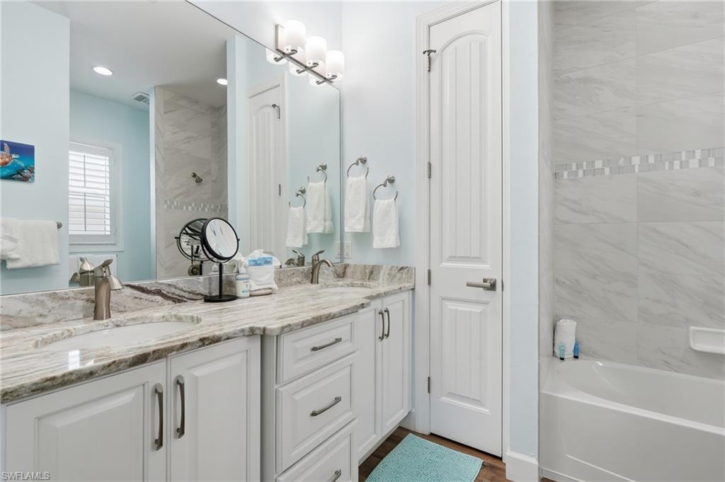 Dual vanity with stone countertop, white cabinetry, and brushed nickel hardware - Virtually Edited Image