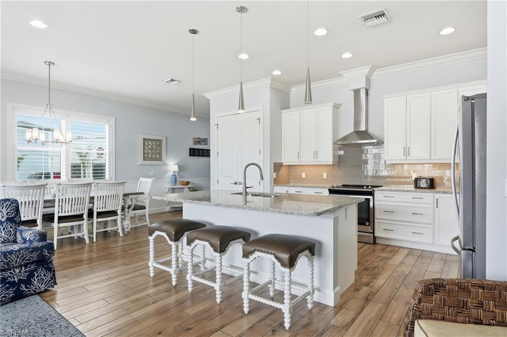 Gourmet kitchen with white cabinetry, stainless steel appliances, granite countertops, and a tiled backsplash - Virtually Edited Image