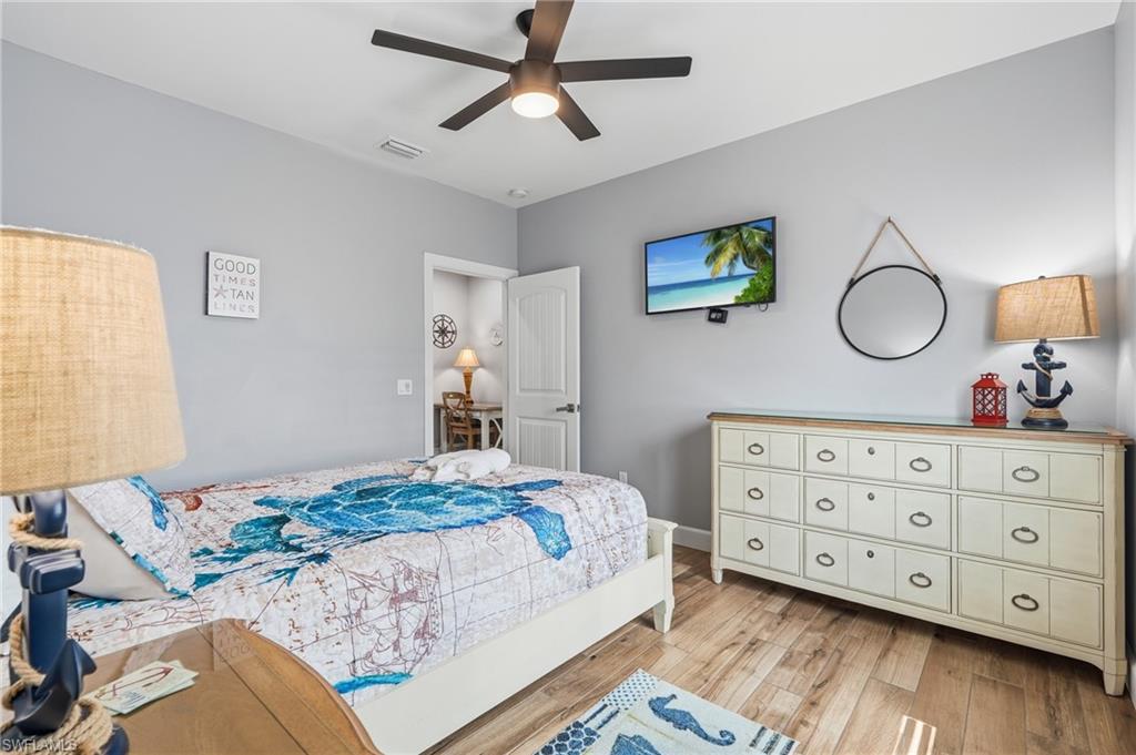 Wood-finish flooring, ceiling fan, neutral wall color, and a multi-drawer dresser - Virtually Edited Image