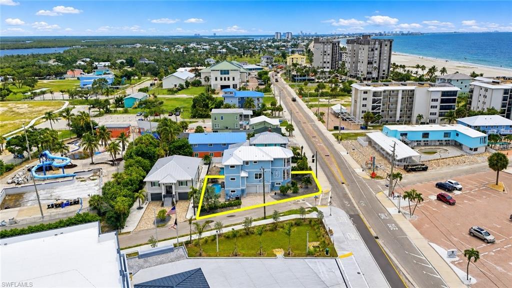 Waterfront property featuring a multi-story residence, a private swimming pool, and proximity to a sandy beach - Virtually Edited Image
