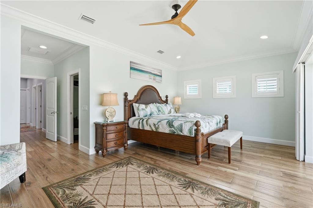Spacious room featuring wood-finish flooring, recessed lighting, and crown molding - Virtually Edited Image