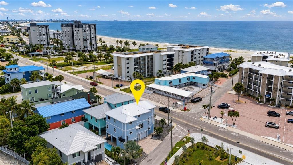 Coastal property featuring a multi-story exterior, multiple balconies, and a paved parking area