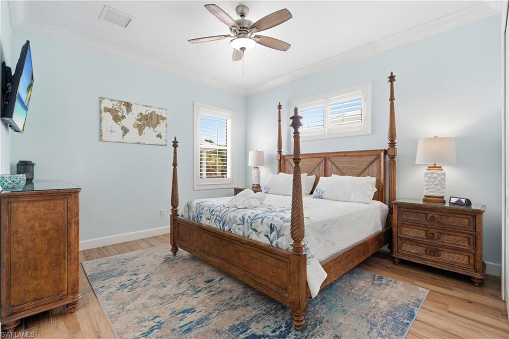 Wood-finish flooring, crown molding, ceiling fan with integrated lighting, and window with plantation shutters - Virtually Edited Image