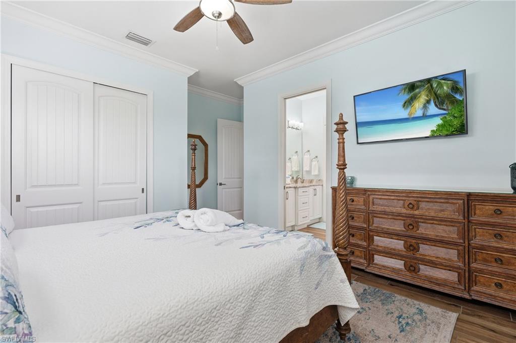 Crown molding detail, wood-finish flooring, ceiling fan, and white paneled closet doors - Virtually Edited Image