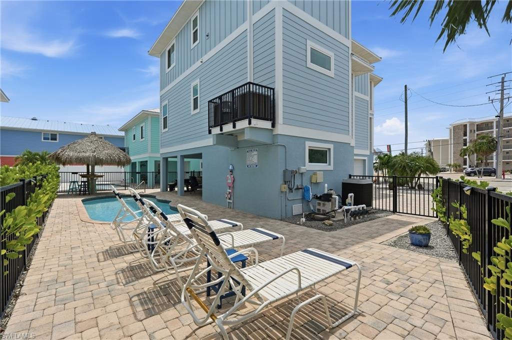 Paver patio with a built-in swimming pool, surrounded by a black metal fence and mature landscaping - Virtually Edited Image