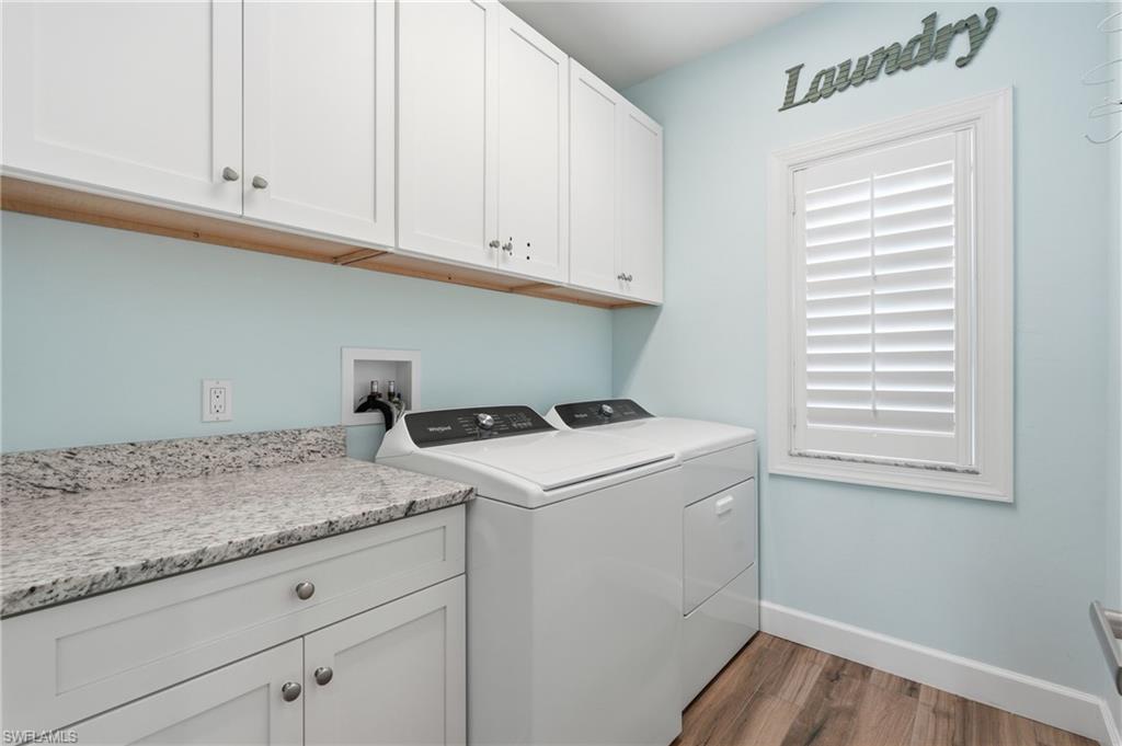 Laundry room with wood-finish flooring, white cabinetry, and a light-toned countertop - Virtually Edited Image