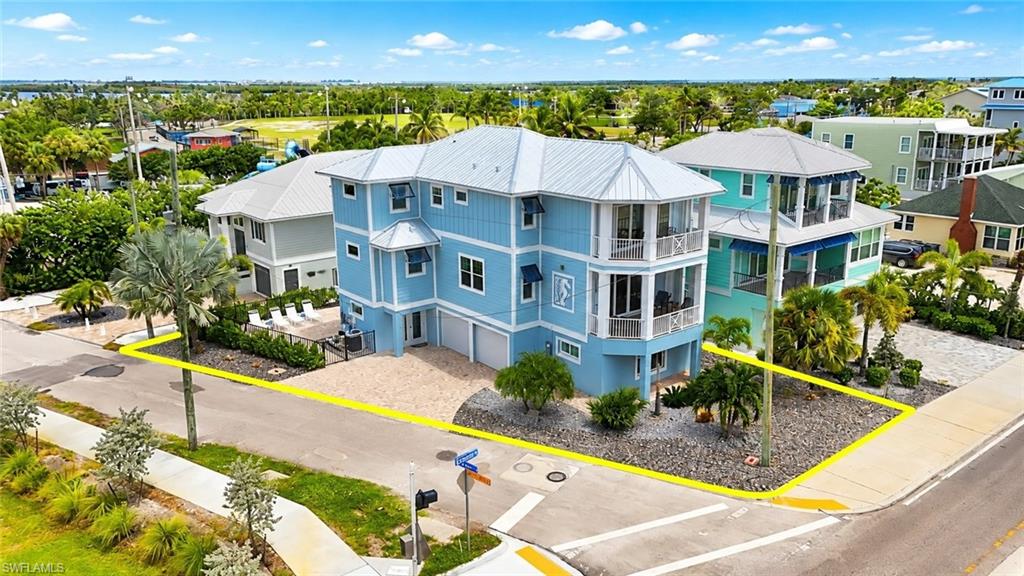 Multi-story coastal residence featuring a metal roof, multiple balconies, and an integrated two-car garage - Virtually Edited Image