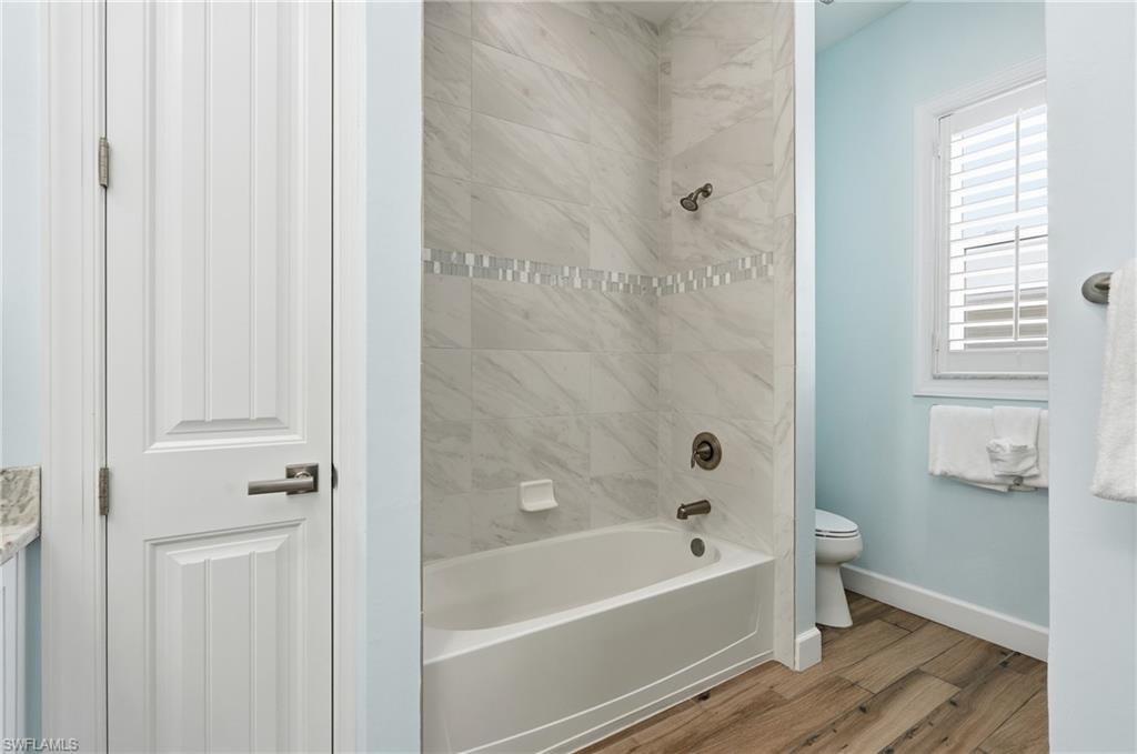 Bathtub with surrounding tile, decorative tile band, and dark bronze fixtures - Virtually Edited Image