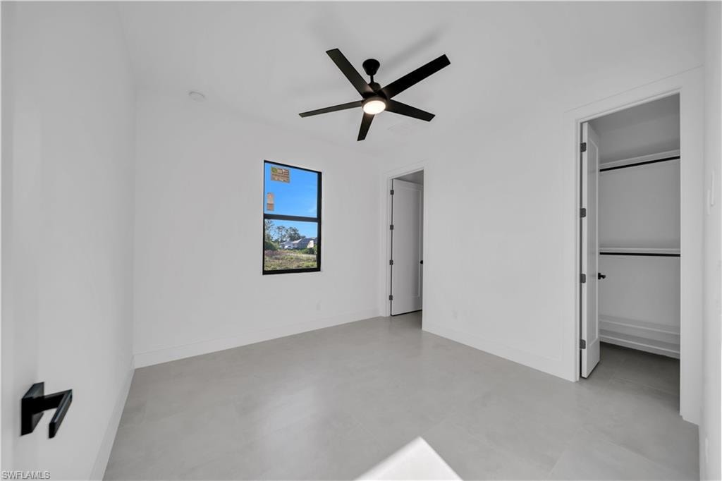 White walls, light-toned flooring, and a black ceiling fan with integrated lighting