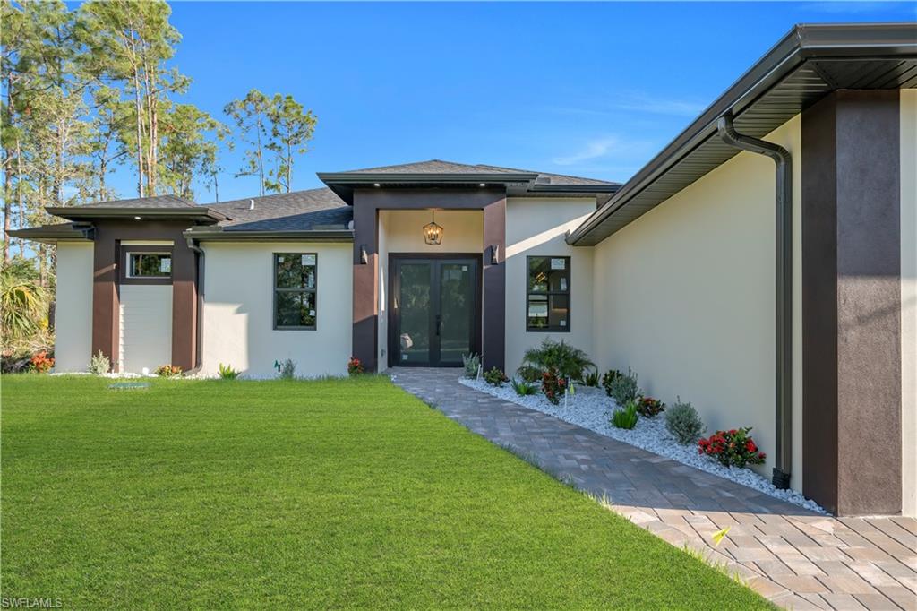 Contemporary exterior with a covered entry, paver walkway, and manicured lawn