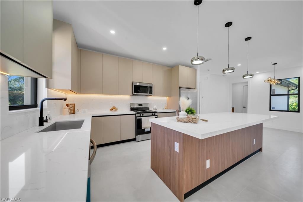 Modern kitchen featuring quartz countertops, stainless steel appliances, contemporary cabinetry, a large center island, and pendant lighting