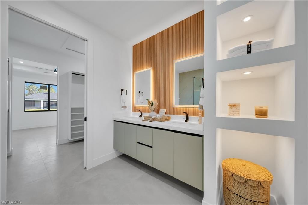 Floating dual vanity with integrated sinks, recessed wall niches with integrated lighting, wood-finish accent wall, and large format floor tiling