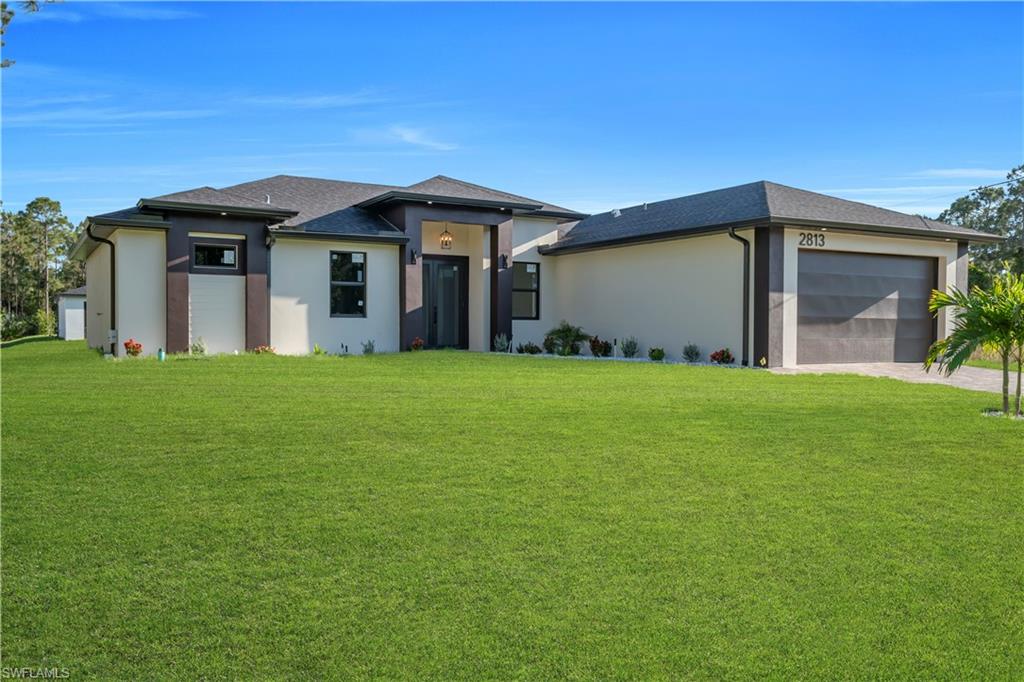 Contemporary exterior with a two-car garage, expansive lawn, and low-maintenance landscaping