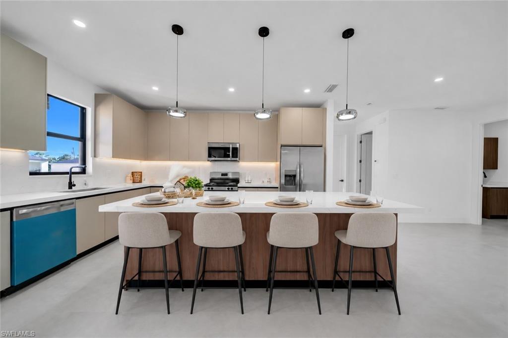 Kitchen featuring a large central island, stainless steel appliances, recessed lighting, pendant lighting, and light-toned cabinetry