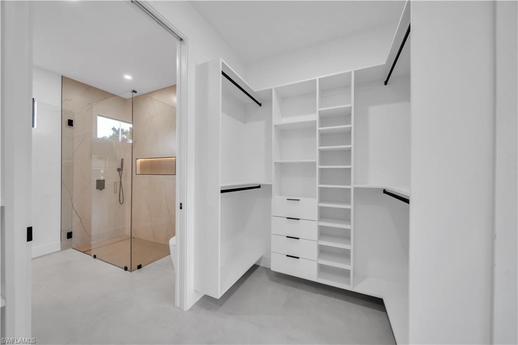 Walk-in wardrobe featuring built-in shelving, integrated drawers, and hanging rods