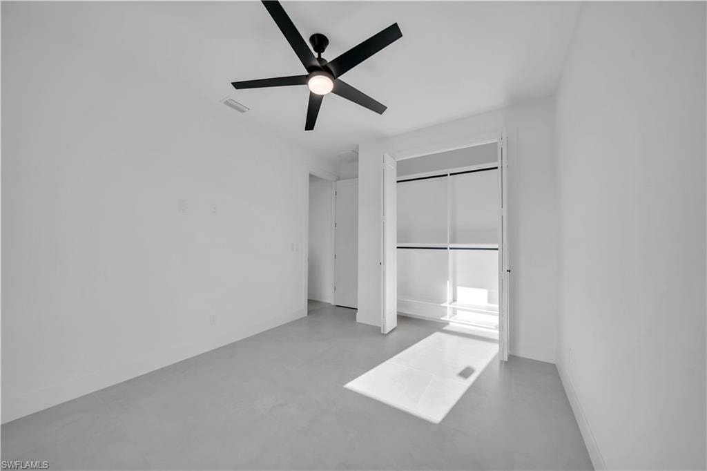 Room featuring a ceiling fan with integrated lighting, a built-in closet with shelving and hanging rods, and light gray flooring