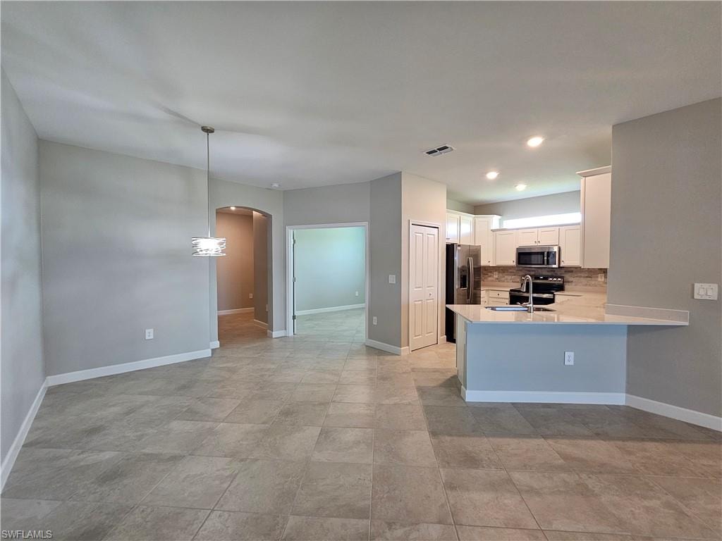 Kitchen island with seating, stainless steel appliances, white cabinetry, tile flooring, and recessed lighting