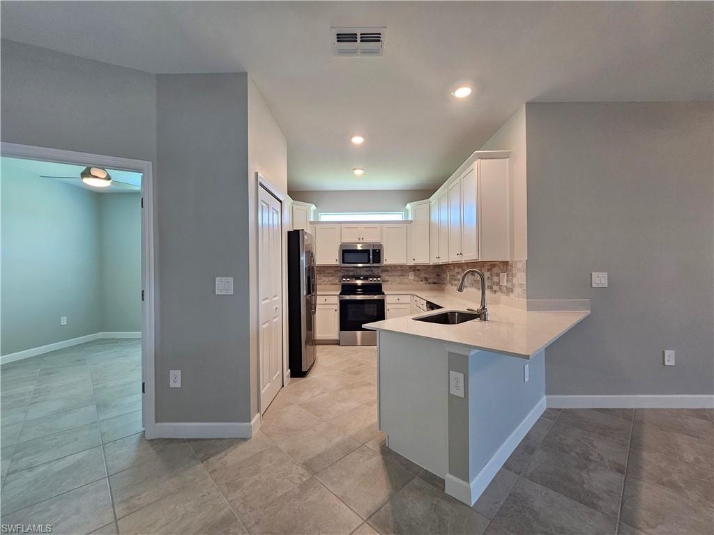 Contemporary kitchen featuring white cabinetry, stainless steel appliances, a tile backsplash, and light-toned countertops