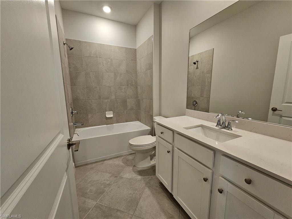 Full bathroom featuring a single vanity with white cabinetry, a built-in tub with tile surround, and tile flooring