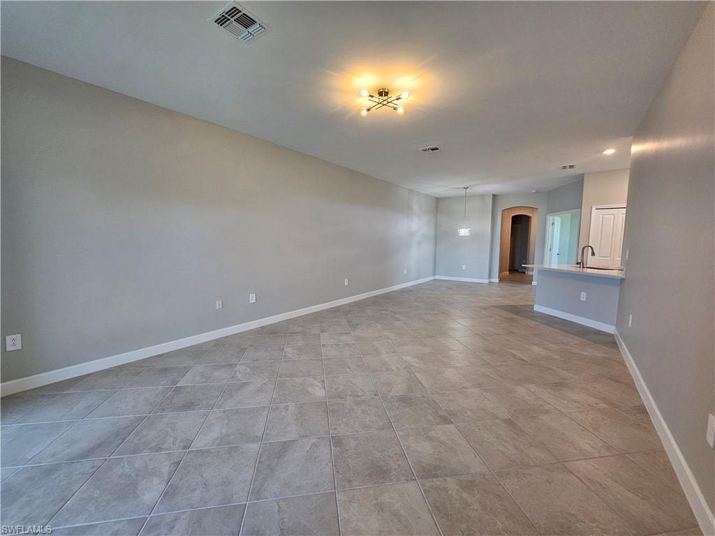 Expansive open-concept room with neutral wall tones, large format tile flooring, contemporary ceiling light fixture, and recessed lighting