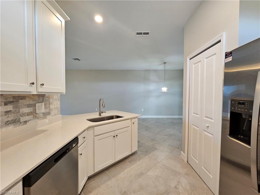 White cabinetry, stainless steel dishwasher, undermount sink with gooseneck faucet, light-toned countertop, and tile flooring