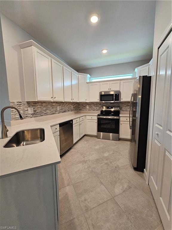 White shaker cabinetry, stainless steel appliances, tile flooring, stone-finish countertops, and a tiled backsplash