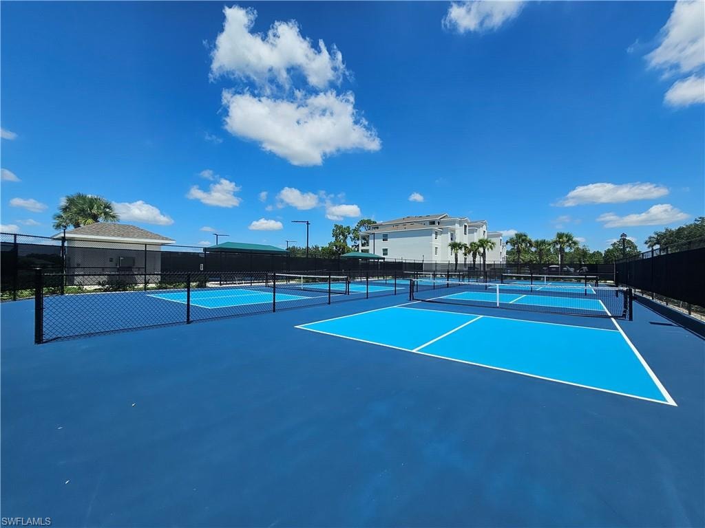 Multiple pickleball courts with blue surfacing, bordered by black chain-link fencing