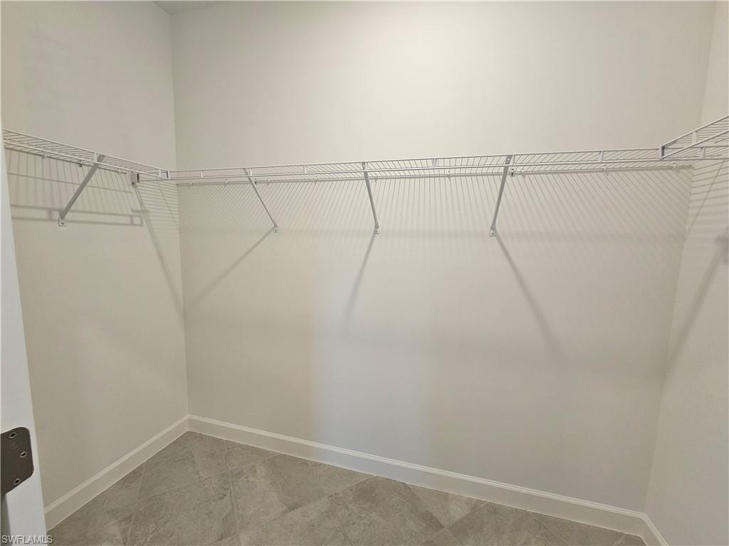 Corner closet with white wire shelving and light-toned tile flooring