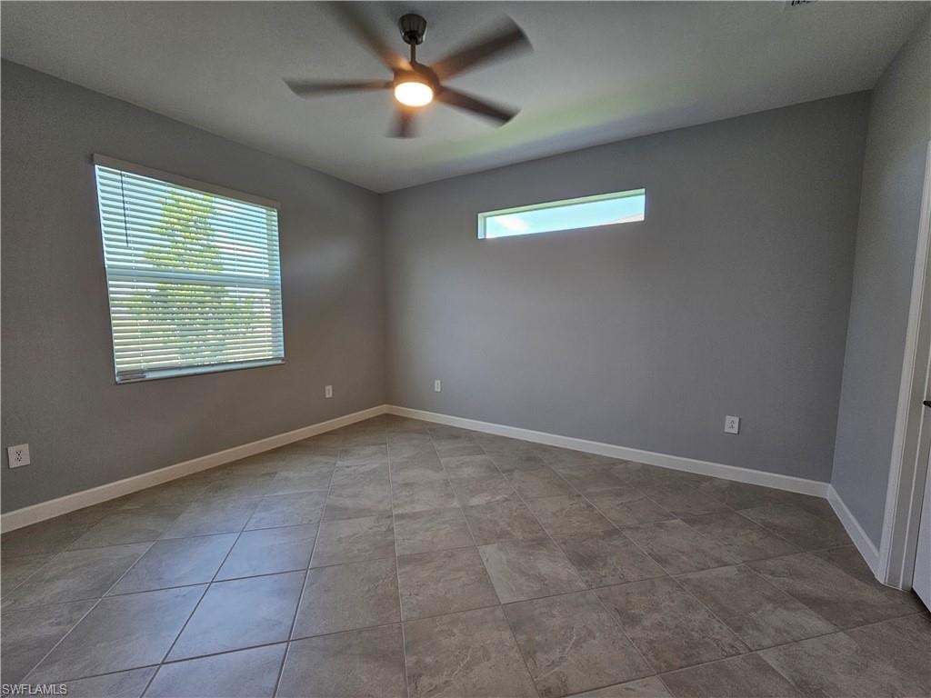 Spacious room featuring tile flooring, ceiling fan with integrated lighting, a large window with blinds, and a transom window