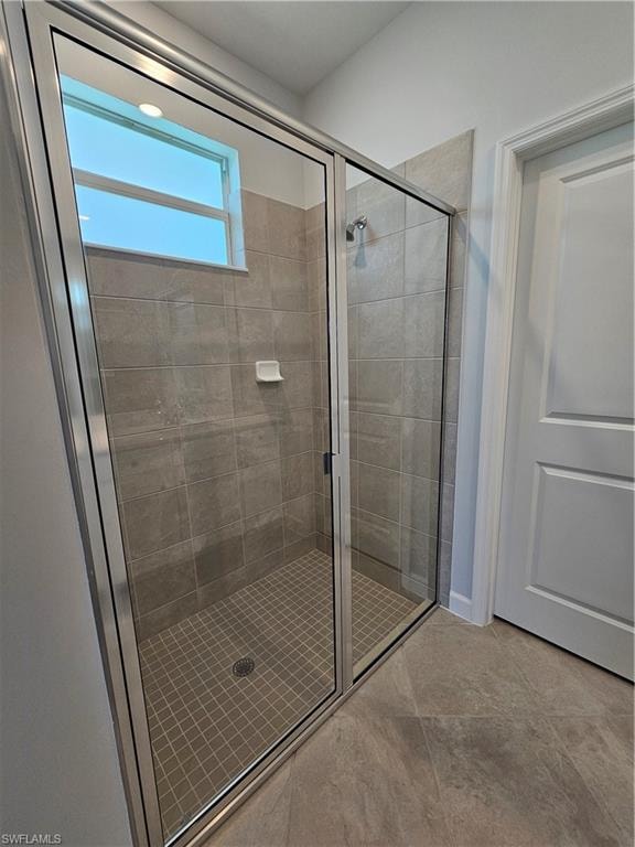 Glass-enclosed shower with tile surround, mosaic tile flooring, and integrated window