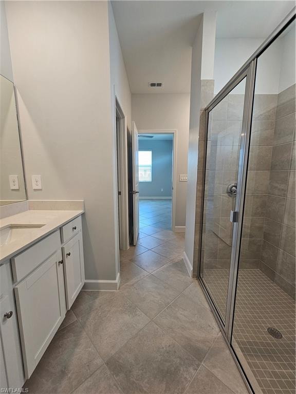 Walk-in shower with glass enclosure, single vanity with light-colored countertop, and tile flooring