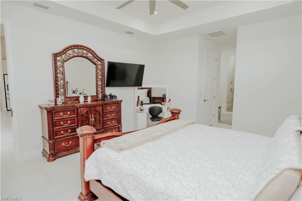 Bedroom with ceiling fan, light tile patterned floors, visible vents, and baseboards