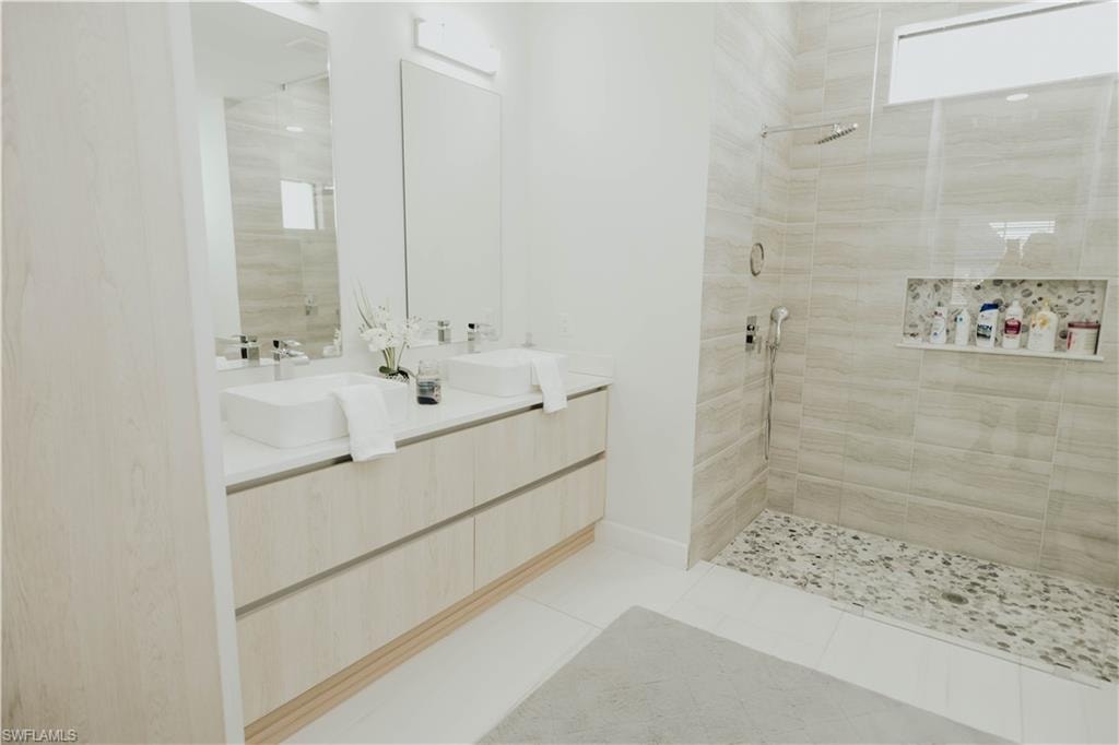 Full bath with a walk in shower, double vanity, tile patterned flooring, and a sink