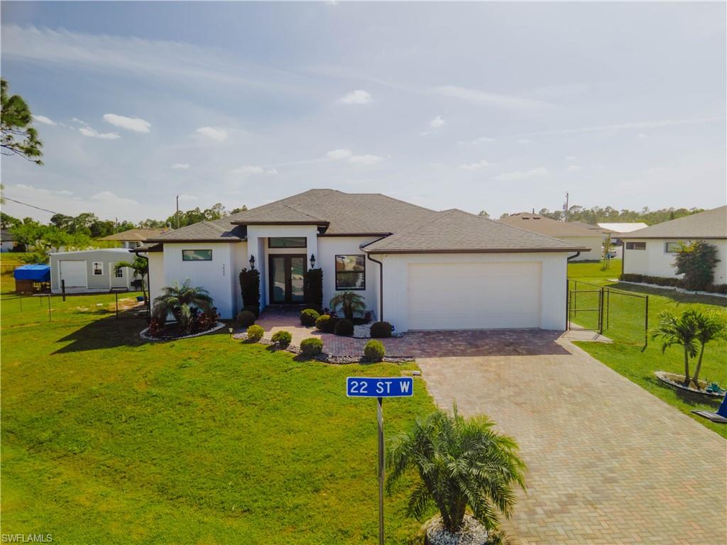 Prairie-style home with a garage, a front lawn, decorative driveway, and fence