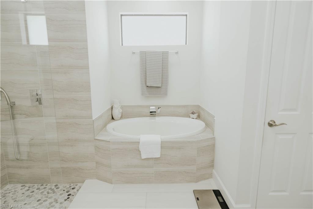 Bathroom with a stall shower, tile patterned floors, and a bath