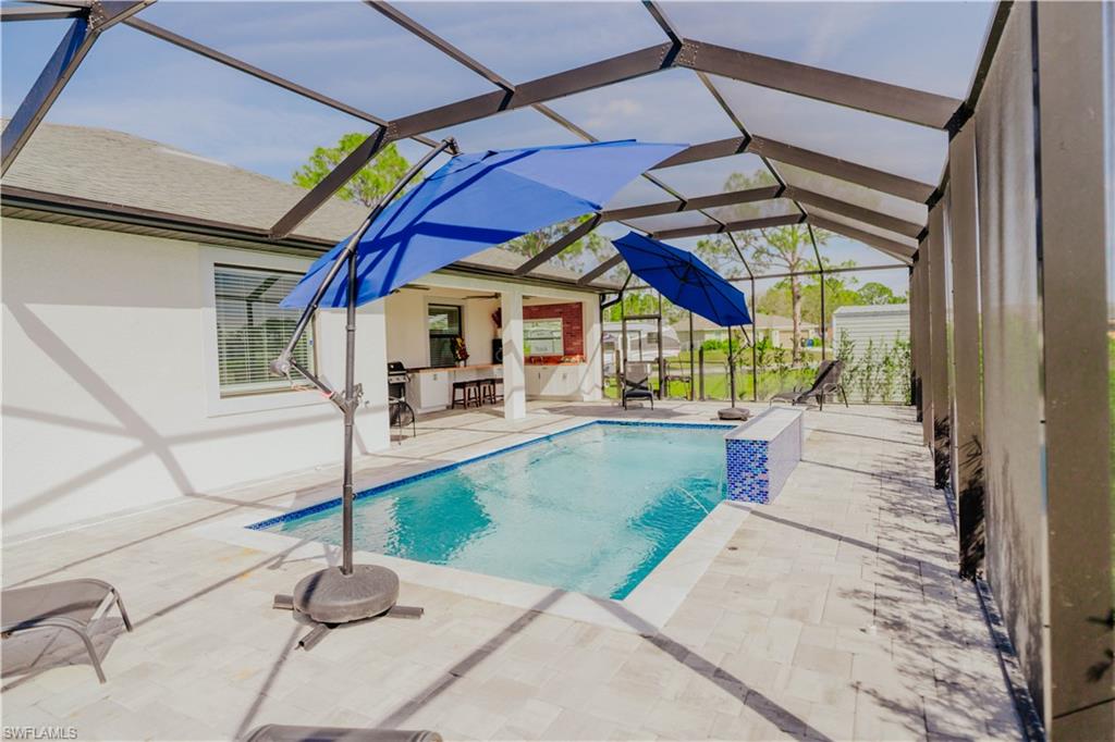 Pool featuring a patio area, glass enclosure, and outdoor dry bar