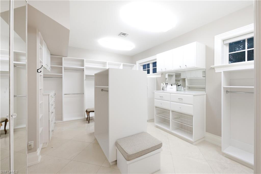 Spacious walk-in closet featuring extensive built-in shelving, hanging rods, and cabinetry