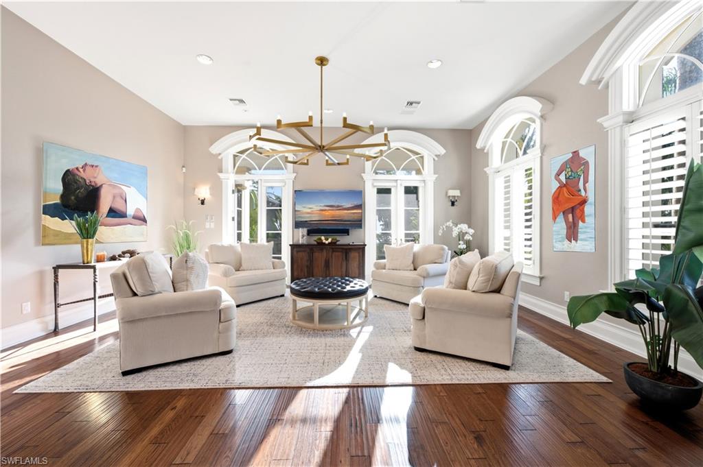 Hardwood flooring, arched windows with plantation shutters, vaulted ceilings, and a multi-arm chandelier