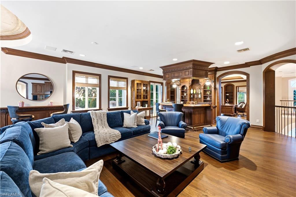 Hardwood flooring, custom built-in bar, arched doorways, and substantial crown molding