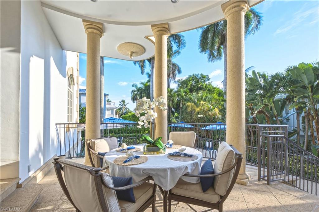 Curved balcony with stone columns, wrought iron railing, and a textured floor