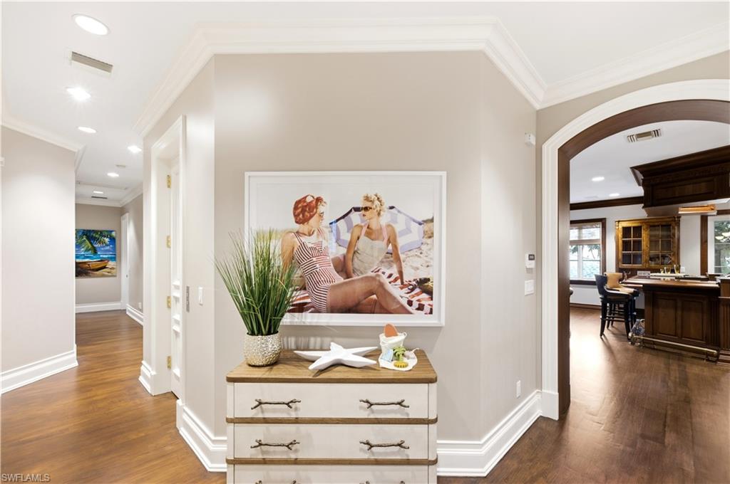 Hardwood flooring, recessed lighting, crown molding, arched entryway, and baseboard trim