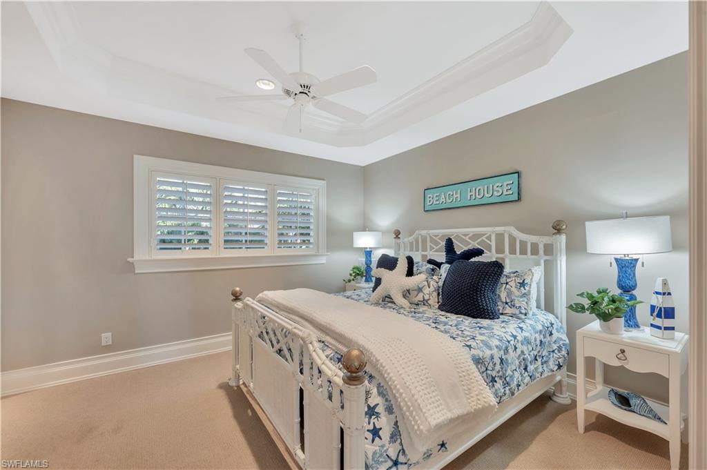 Tray ceiling with crown molding, white ceiling fan, plantation shutters, neutral wall paint, and white trim