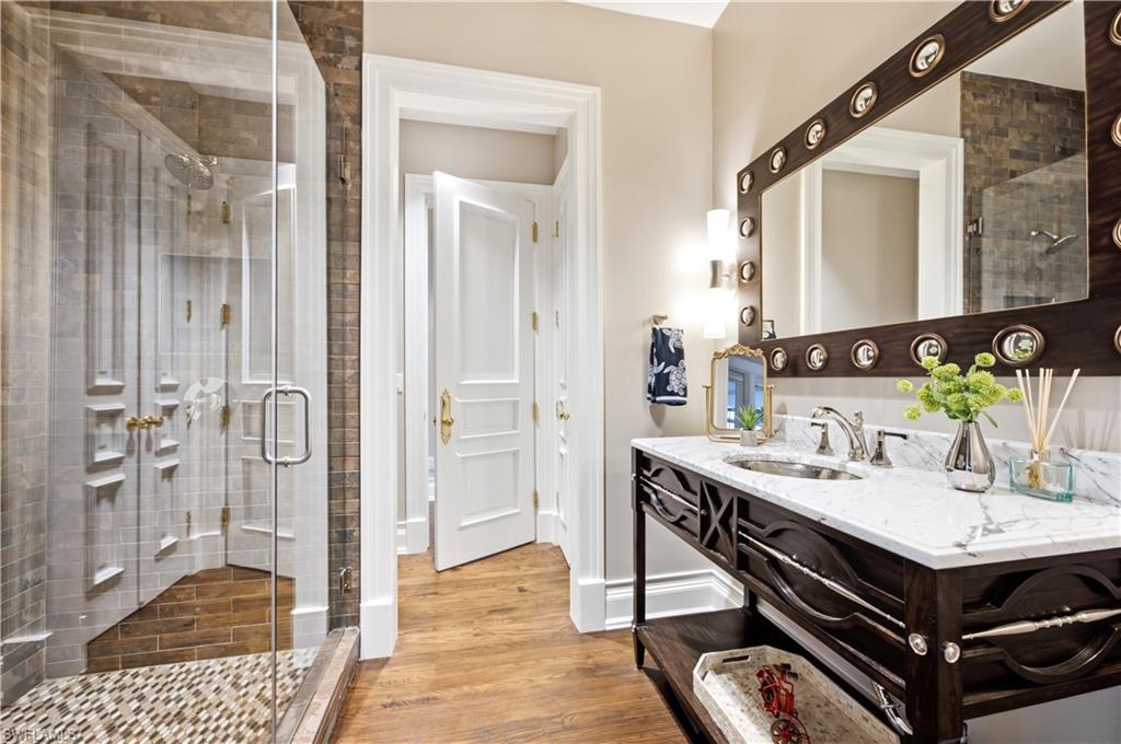 Glass-enclosed shower with mosaic tile flooring and light-toned wall tiling