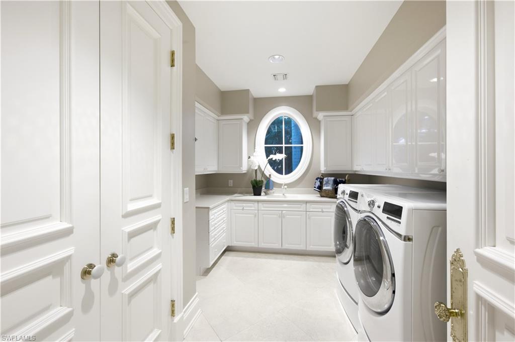 Laundry room featuring an oval window, extensive white cabinetry, light-toned flooring, integrated sink, and recessed lighting
