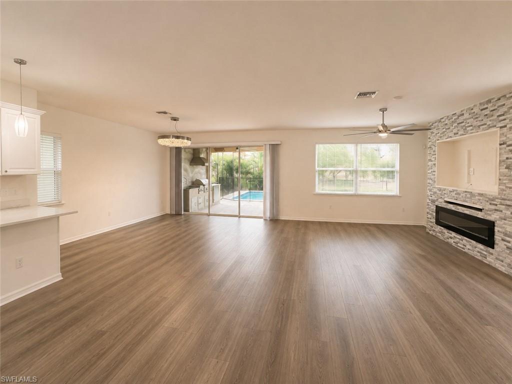 Wood-finish flooring throughout, featuring a built-in electric fireplace with stone tile surround, recessed wall niche, and ceiling fan
