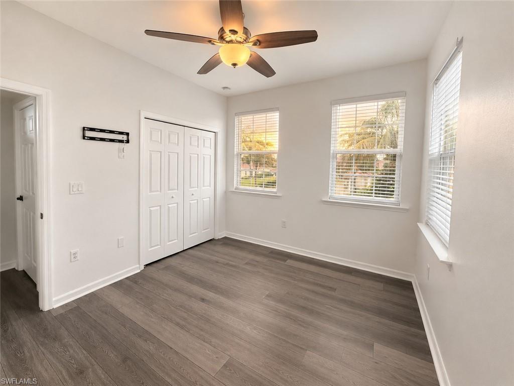 Wood-finish flooring, white walls, and a ceiling fan with integrated lighting