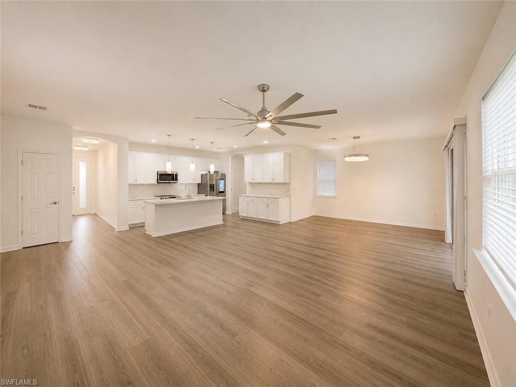 Open-concept living space featuring wood-finish flooring, white kitchen cabinetry, a kitchen island, and a ceiling fan